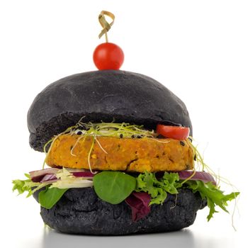 Tasty grilled veggie burger with chickpeas and vegetables on black bread on white background.