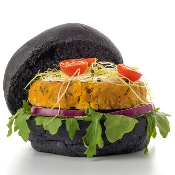 Tasty grilled veggie burger with chickpeas and vegetables on black bread on white background.