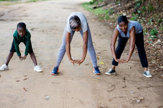two active women with child in sportswear exercising stretching on the track in the park