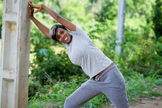 Young woman warms up and stretches her arms against a wall outside the morning sport. Health and Sport Concept