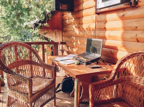 workplace in an open area in the garden with wicker furniture under the grapes. A place for a freelancer. The concept of free work.