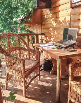workplace in an open area in the garden with wicker furniture under the grapes. A place for a freelancer. The concept of free work.