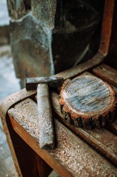 an old vintage hammer and a round bar of pine with sawdust on a bench. A wooden food stand for a master class. DIY concept.