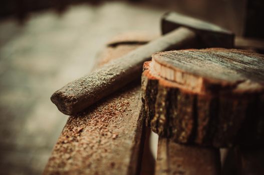 an old vintage hammer and a round bar of pine with sawdust on a bench. A wooden food stand for a master class. DIY concept.