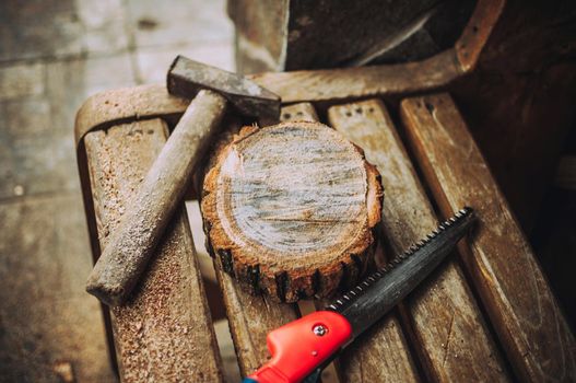 an old hammer, a hand saw and a round bar of pine with sawdust on a bench. Wooden stand for food for the master class. DIY concept.