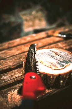 A hand saw cuts a piece of wood from a round beam and pines on a bench. Around the wreckage and sawdust. A wooden stand for food for the master class. DIY concept.