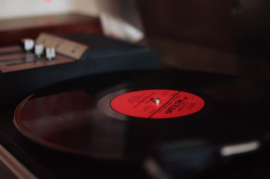 Vinyl record player on a sunset background over the city lights. Sound technology for DJs to mix and play music. Black vinyl record. 1980 vintage vinyl wood record player. Vinyl record needle