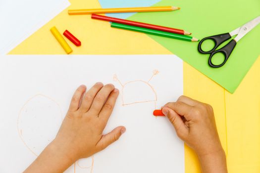 Indoor activity. Top view of kid's hands paiting with crayons. Indoor activity