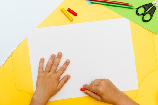 Indoor activity. Top view of kid's hands paiting with crayons. Indoor activity