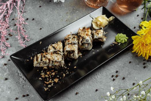 Golden dragon sushi roll with tuna, eel, cucumber, sesame seeds and tobiko caviar on wood background.