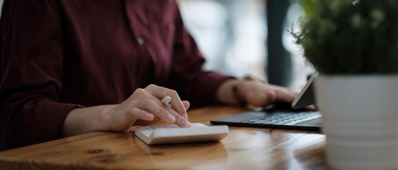 Close up hand of accountant working with computer and calculator for business and financial expense.