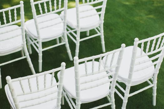 Beautiful white wedding chairs at the ceremony in the Park.