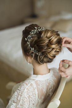 The stylist does the bride's hair in the hotel room