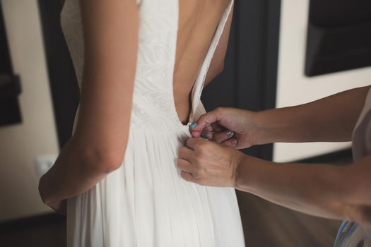 A friend helps to dress the bride's wedding dress