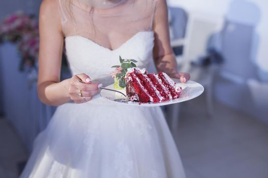 the bride holds a plate with a wedding cake