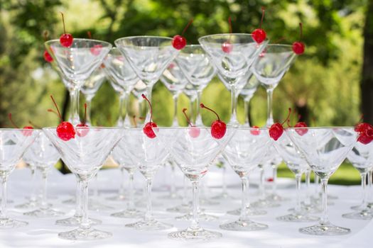 Close-up of the champagne pyramid with a red cherry at the top of each glassGlass goblets. Pyramid of champagne. A celebratory drink. Decorations for the Banquet.