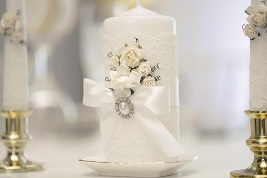 Wedding decor in white style with crystals, lace and flowers. Wedding candles for the family hearth