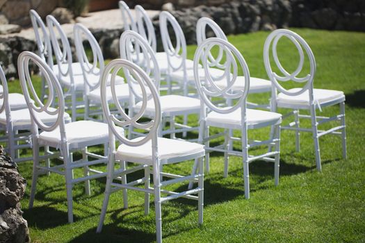 White chairs for guests at the wedding ceremony.