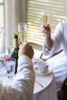 A couple in dressing gowns in a hotel drinking champagne.