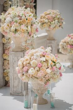 Beautiful bouquet of roses in a vase on a background of a wedding arch. Beautiful set up for the wedding ceremony.