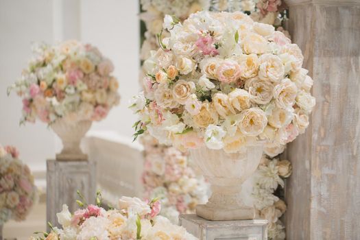 Beautiful bouquet of roses in a vase on a background of a wedding arch. Beautiful set up for the wedding ceremony.