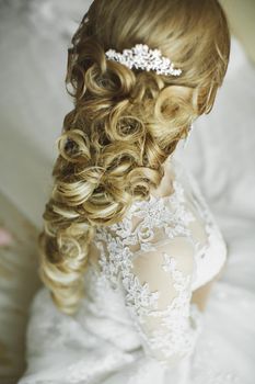 Hair stylist makes the bride a wedding hairstyle with fresh flowers