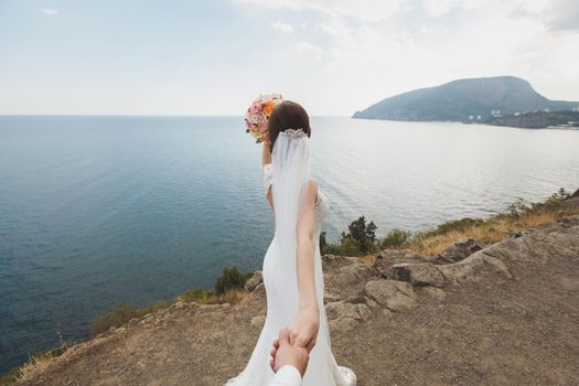 Beautiful young woman bride holds the hand of a man in outdoors. Follow me