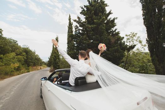 Beautiful stylish young successful couple enjoying riding in the car at wedding walk in the tropical country or island