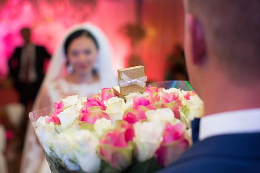 The groom gives the bride flowers and a gift at the wedding Banquet