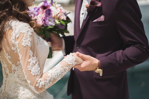 Close-up of the groom holding the bride's hand during the ceremony.