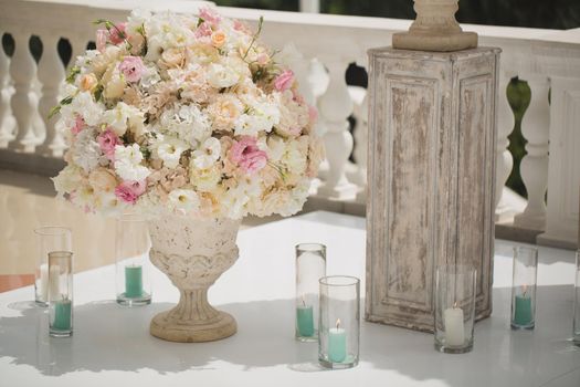 Beautiful bouquet of roses in a vase on a background of a wedding arch. Beautiful set up for the wedding ceremony.