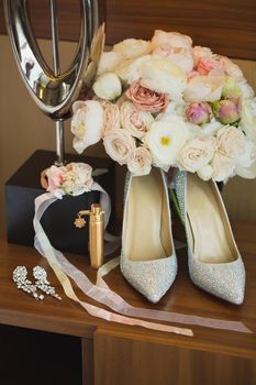 Wedding details. Accessories for the bride: shoes, a bouquet of flowers, jewelry.