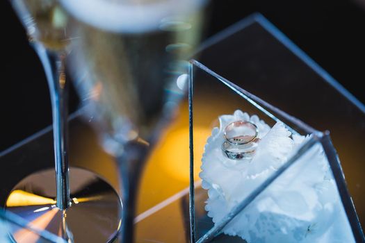 Beautiful elegant wedding rings in a glass box on a white flower.