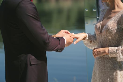 The groom puts the ring on the bride's finger in close-up