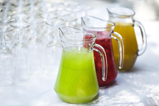 A set of empty glasses displayed in rows. Decanters with colored lemonade.