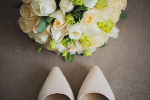 The bride's wedding accessories: shoes and a luxurious bouquet of flowers.