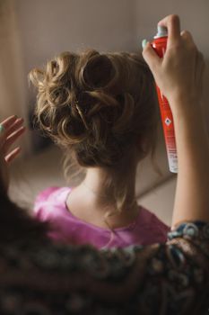 Master stylist makes the bride wedding hairstyle using spray lacquer fixing