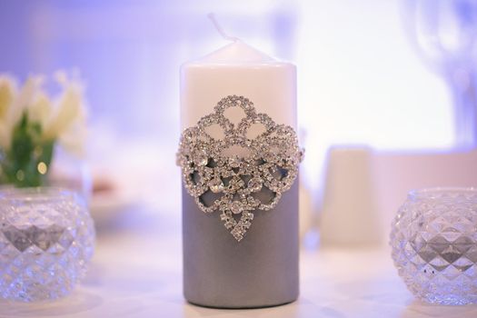 Wedding decor in silver style with crystals, lace and flowers. Wedding candles for the family hearth