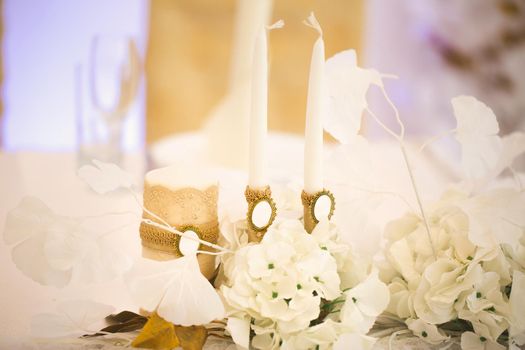 Wedding decor in white and gold style with crystals, lace and flowers. Wedding candles for the family hearth
