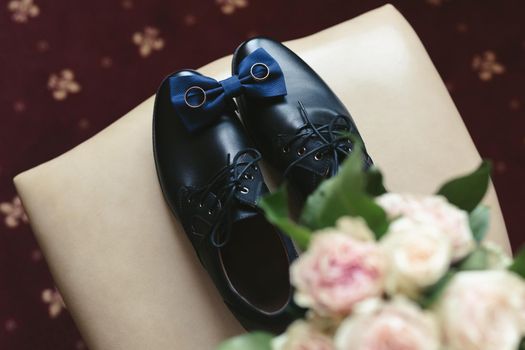 Men's shoes , bouquet, tie and rings on a chair. The view from the top