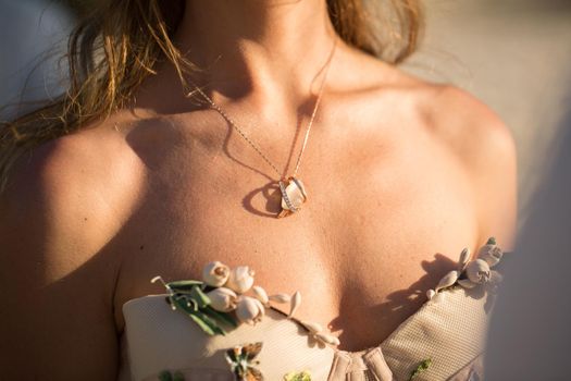 a medallion on a girl's neck during sunset