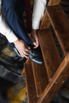 Man tying shoes laces on the wooden floor