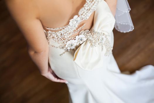 Bridesmaid makes bow-knot on the back of brides wedding dress