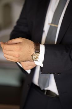 A man in a suit puts a watch on his hand