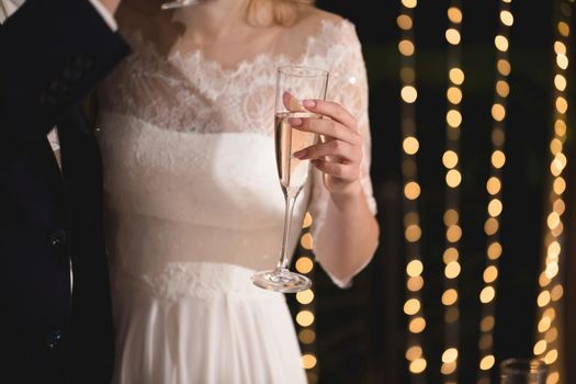 The bride and groom hold crystal glasses filled with champagne