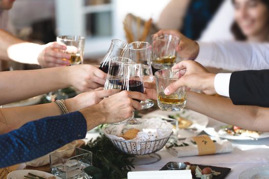 Celebration, eating and holidays concept - hands clinking wine glasses