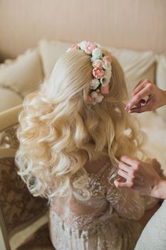 Bride's fees in the morning on the wedding day. Beautiful hairstyle and headband made of fresh flowers.