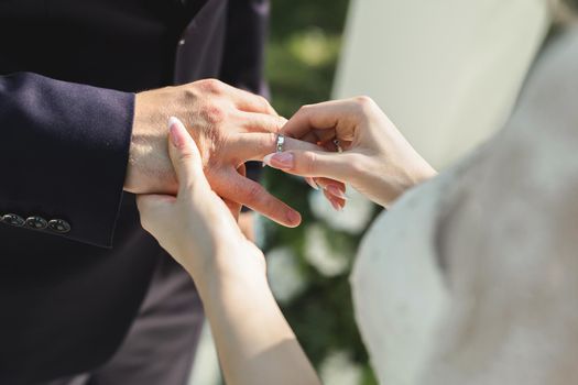The bride puts a ring on the groom's finger in close-up