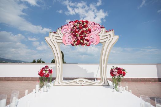 Arch with fresh red flowers on a background of sea and blue sky