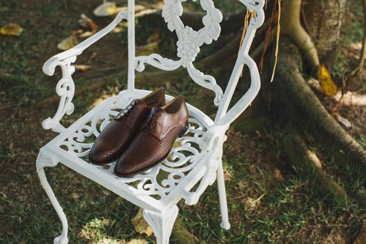 Men's shoes on a white chair on the wedding day.